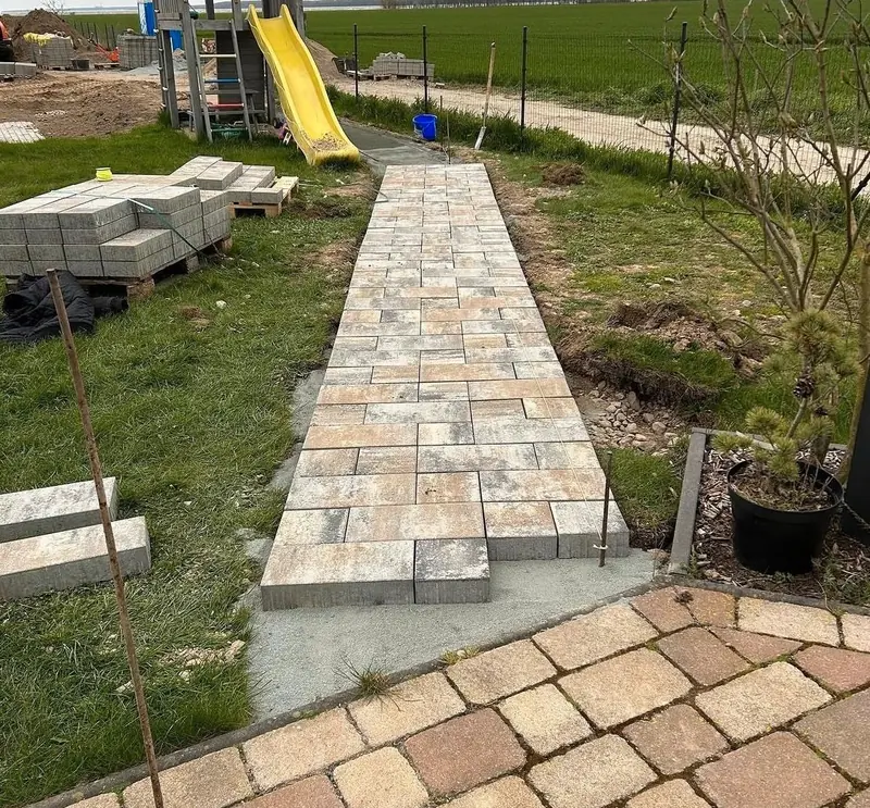 Gartenweg im Bau: Die Pflastersteine werden auf das vorbereitete Bett gelegt